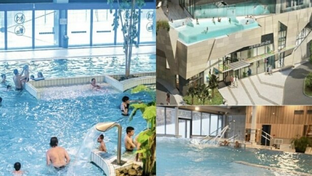 A modern indoor swimming pool with multiple sections, including a hot tub area, surrounded by natural rock formations.