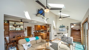 Un vaste espace de vie doté d’un haut plafond, de ventilateurs de plafond et d’un coin repas avec des meubles en bois.