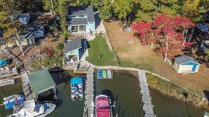 Vue aérienne d’une propriété au bord du lac, avec un quai, des bateaux, une maison et un petit abri.
