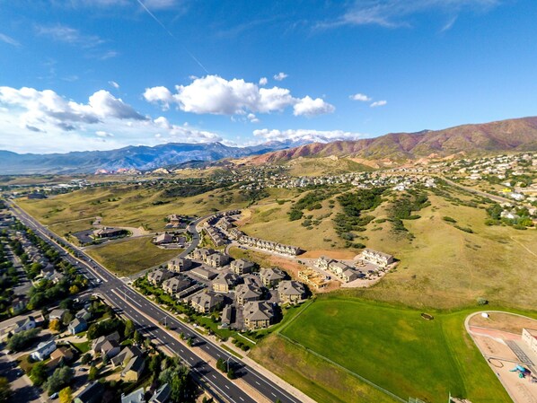 An aerial view of a residential area with houses, roads, and a large green field.
