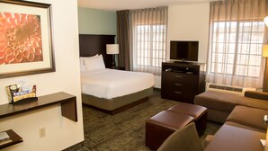 Een hotelkamer met een bed, een televisie, een bureau, een stoel en een bank.