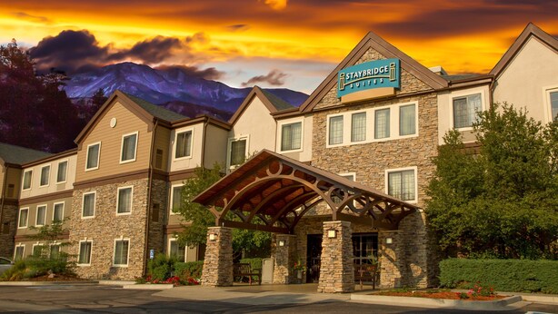 Een Staybridge Suites hotel met een stenen gevel, meerdere ramen en een overdekte ingang.