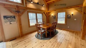 A dining area with a wooden table and chairs, large windows, and a wooden ceiling. - Lakeside Haven - Ice fishing, Snowmobiling, Skiing (Denmark)