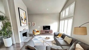 Een moderne woonkamer met een grijze bank, een salontafel, een televisie en een open haard.