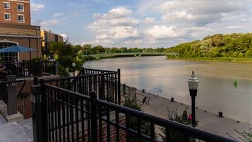 A riverside walkway with a bridge, a building with a blue awning, and a lamp post.