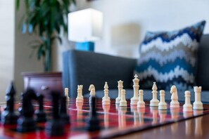 A chessboard with pieces in a living room setting.