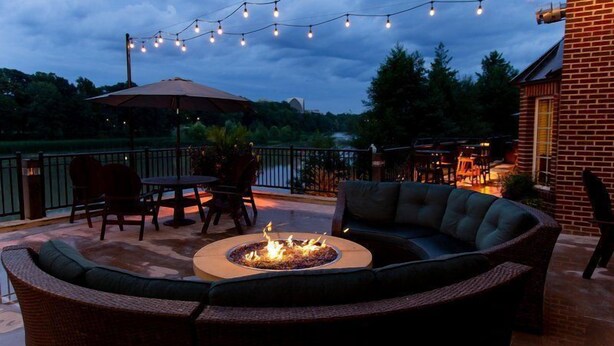 An outdoor patio with a fire pit, seating, and string lights. - Suite Near Rochester University | Gym Access (Rochester)