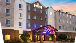 A Staybridge hotel with a brick facade, multiple windows, and a covered entrance area. - Suite Near Rochester University | Gym Access (Rochester)