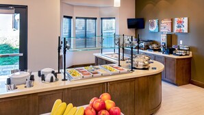 Un comptoir pour le petit-déjeuner avec des fruits, un espace dédié au café et un téléviseur fixé au mur.
