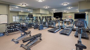 A gym with various exercise equipment, including treadmills, elliptical machines, and free weights.