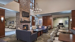 A spacious lobby with a stone fireplace, comfortable seating, and a large chandelier.