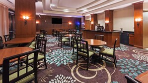 A hotel lobby with multiple dining tables and chairs, a bar area, and a patterned carpet. - Comfy Studio Suite | Free Breakfast + Outdoor Pool (San Antonio)