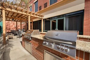 An outdoor kitchen with a grill, seating area, and a pergola. - Comfy Studio Suite | Free Breakfast + Outdoor Pool (San Antonio)