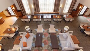 Een hotel lobby met een centraal zitgedeelte, meerdere tafels en stoelen eromheen.