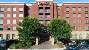 A Staybridge Suites hotel with a brick facade, multiple windows, and a central entrance. - King Studio | Less than 1 Mile from USC (Columbia)