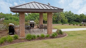 A covered patio area with brick pillars, outdoor furniture, and a grill. - King Studio | Less than 1 Mile from USC (Columbia)