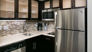Une cuisine moderne avec des meubles de couleur sombre, des appareils en acier inoxydable, un pare-feu en carrelage et un lave-vaisselle.