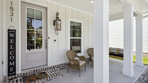 A porch with a welcome sign, two wicker chairs, and a door marked with the number 1531.