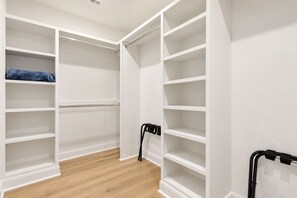 A walk-in closet with white shelving and a wooden floor.