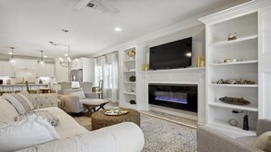 A modern living room with a large flat-screen TV, comfortable seating, and built-in shelving.