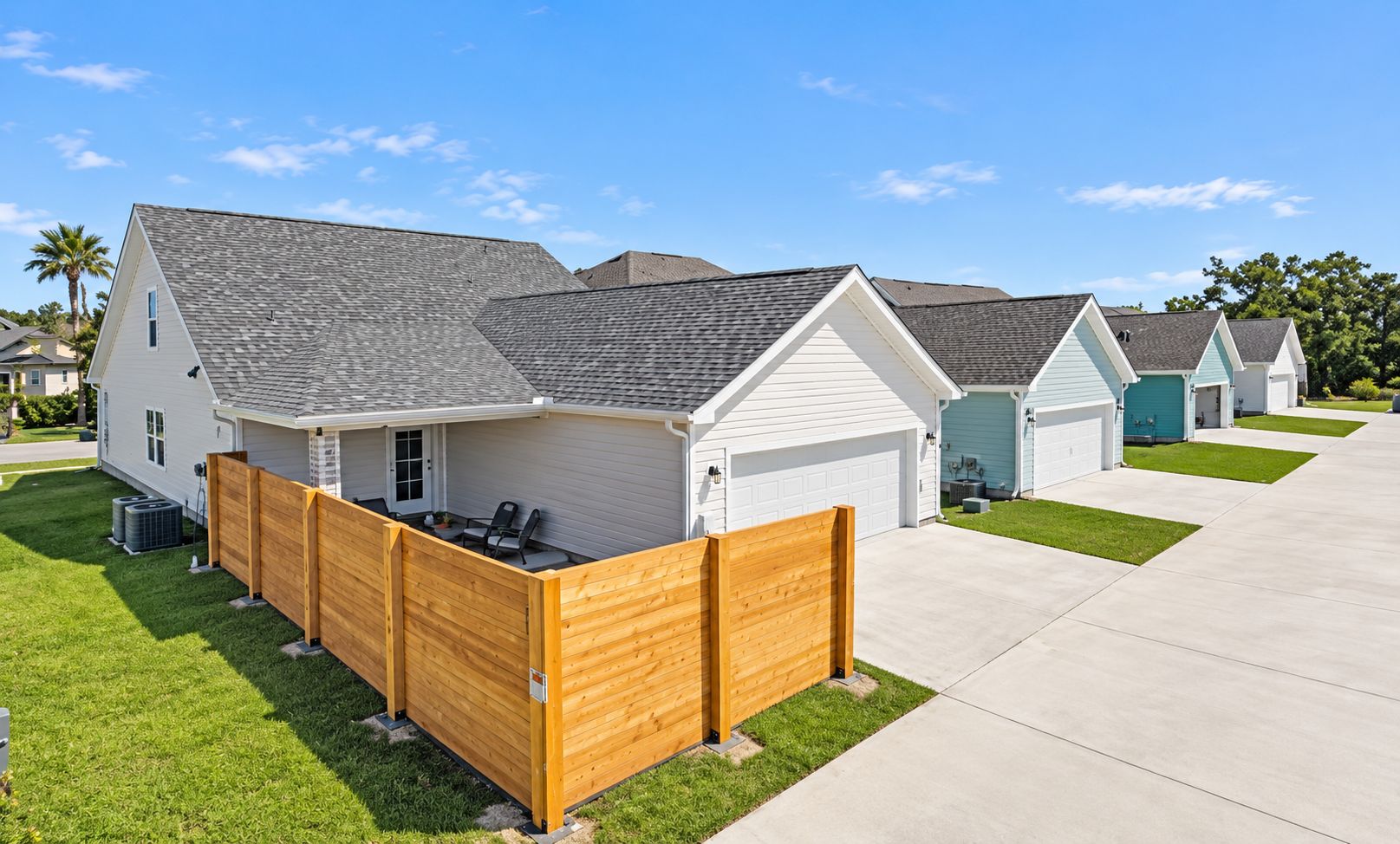 A residential area with houses, a driveway, and a wooden fence.