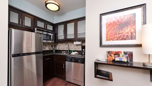 Una cocina moderna con electrodomésticos de acero inoxidable, armarios de madera oscura y salpicadero de azulejos.