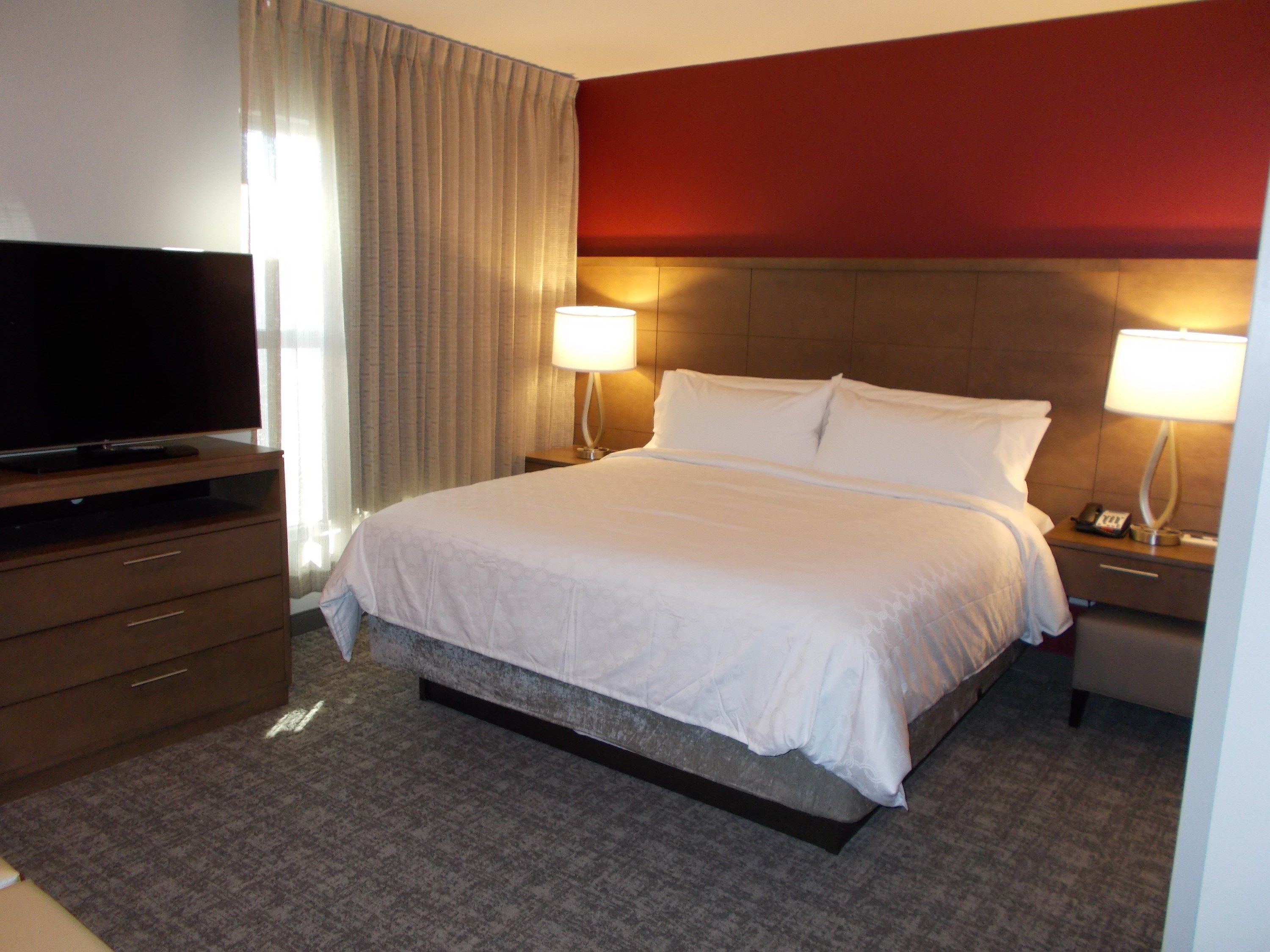 Een hotelkamer met een bed, een televisie, een nachtkastje en een lamp.