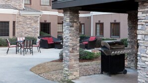 An outdoor patio with stone pillars, a grill, and outdoor furniture. - 1 Bedroom Suite | Outdoor Pool, Free Breakfast (Ridgeland)