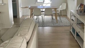 Une cuisine moderne avec un coin repas, des meubles blancs et une grande fenêtre.