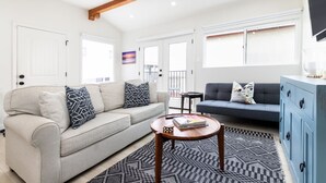 Un salon avec un canapé beige, un canapé bleu foncé, une table basse en bois et un meuble bleu.