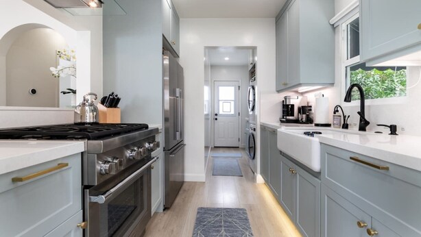 Une cuisine moderne dotée d’appareils électroménagers en acier inoxydable, de meubles de couleur gris clair et d’un îlot central.