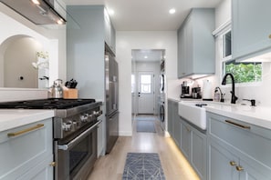 Una cocina moderna con electrodomésticos de acero inoxidable, armarios de gris claro y una isla central.