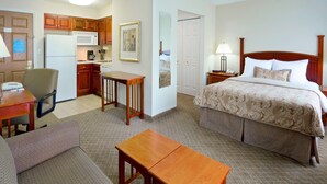 A hotel room with a bed, a desk, a chair, a small table, a microwave, a refrigerator, and a kitchenette. - Studio w/ Kitchen | Free Breakfast Buffet (Cranbury)