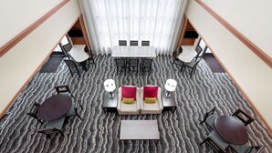 Un hall d’hôtel doté d’un espace salon central, d’un escalier et d’une vue sur l’étage supérieur.