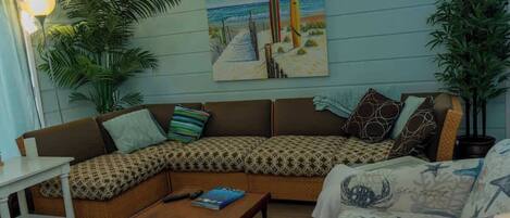 A cozy living room with a sectional sofa, a coffee table, and a painting of a beach scene.
