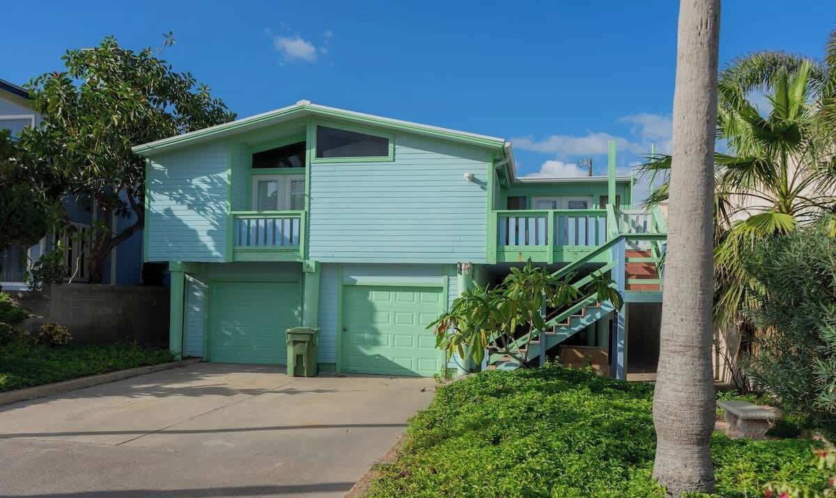 A two-story house with a green exterior, a front garage, and a staircase leading to the second floor.