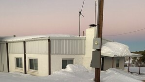 Ein mit Schnee bedecktes Industriegebäude mit Metallbedachung und großen Fenstern.