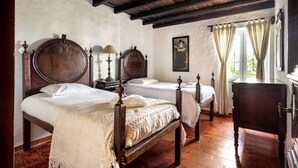 Ein traditionelles Schlafzimmer mit zwei Holzbetten, einer Holzkommode und einer rustikalen Decke.
