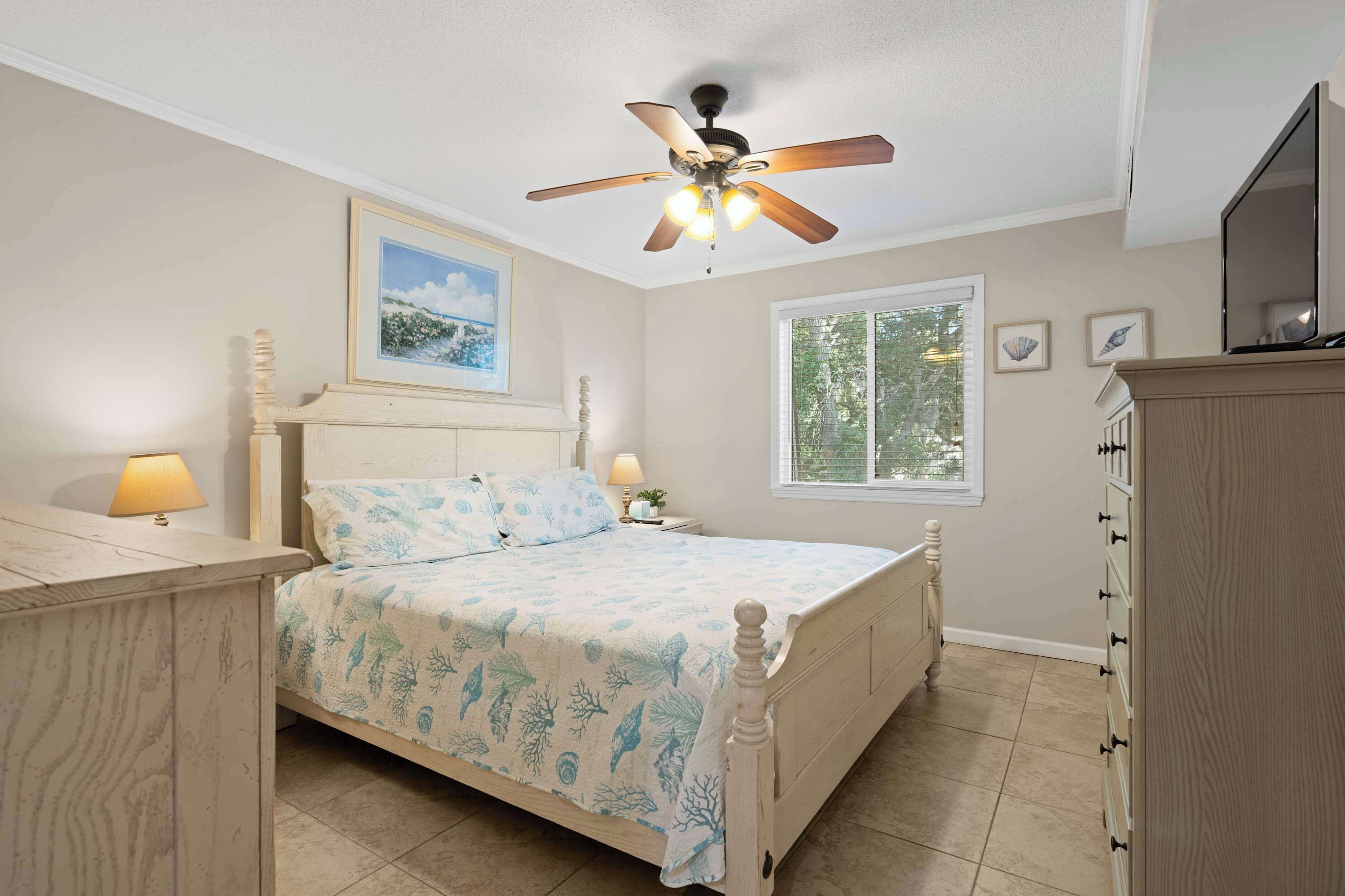 A bedroom with a bed, nightstands, a ceiling fan, a window, and a dresser.