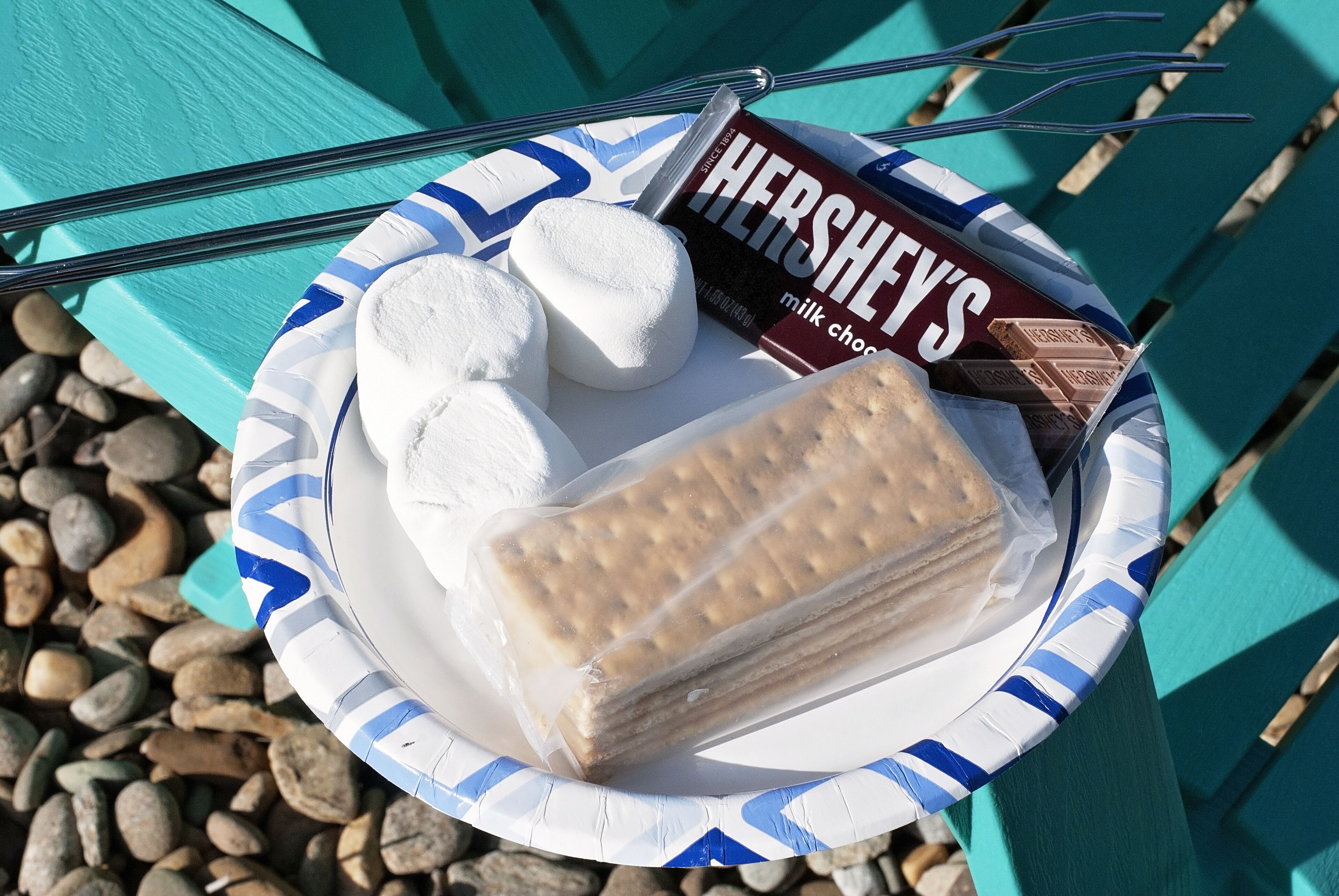 Une assiette en carton contenant une barre de chocolat au lait Hershey's, deux guimauves et une barre de chocolat rectangulaire.