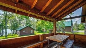 A wooden deck with benches and a table, overlooking a lake and cabins. - Rustic Cabin Retreat on Rangeley Lake! (Rangeley)