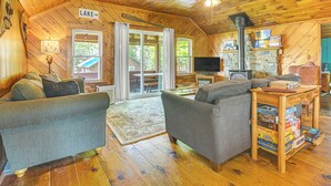 A cozy cabin interior with a fireplace, wooden floors, and a couch. - Rustic Cabin Retreat on Rangeley Lake! (Rangeley)