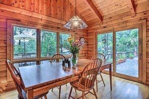 A wooden cabin with a dining table, chairs, and a vase of flowers.