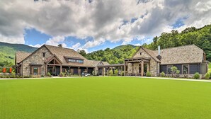 A large, modern house with a spacious lawn, stone exterior, and multiple entry points. - 'Cold Mountain Reflections' Cabin w/ Game Room! (Canton)