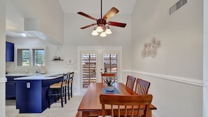 A spacious kitchen with a central island, a dining area with wooden chairs, and a ceiling fan. - Spring Training, Heated Pool, Big Yard, Grill, Quiet Neighborhood (Peoria)