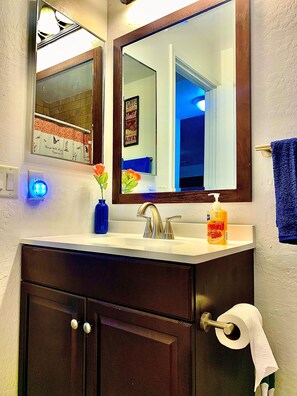 Ein Badezimmer mit Waschbecken, Spiegel und Toilettenpapierhalter.
