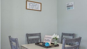 A dining table with a sign that reads "Gather together" and a vase with flowers.