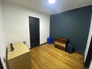 Compact room with a simple layout, featuring a dresser and a door leading to another space.