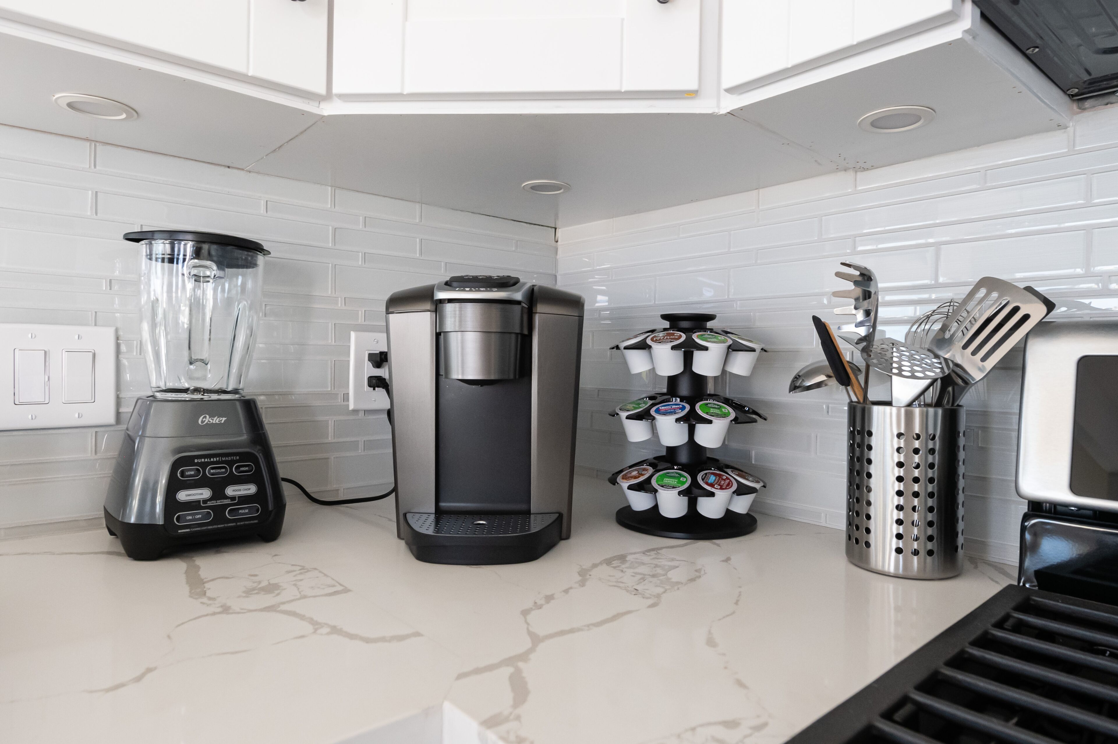 A kitchen with a blender, coffee maker, and utensil holder.