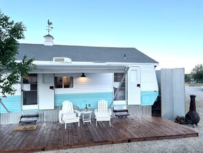 Une maison mobile dotée d’une terrasse, de meubles blancs et d’un barbecue.